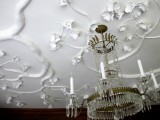 this molding imitates flowers and looks very natural, as if they are growing on the ceiling and a crystal chandelier adds to the space