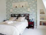 a neutral bedroom with a blue printed headboard wall that brings in a touch of color and pattern to the space