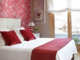 a red floral accent wall in deep red and a matching blanket and pillows give timeless elegance to the bedroom