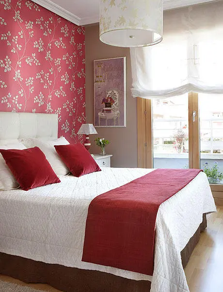a red floral accent wall in deep red and a matching blanket and pillows give timeless elegance to the bedroom