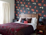 an exquisite bedroom with a dark floral accent wall and a dark blanket on the bed plus matching pillows
