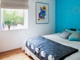 a bedroom spruced up with a super bright and colorful wallpaper accent wall that takes over the whole room