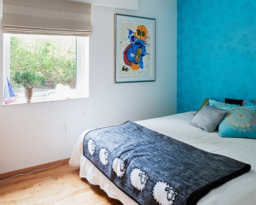 a bedroom spruced up with a super bright and colorful wallpaper accent wall that takes over the whole room