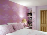 a girlish bedroom with a pink floral accent wall and matching bedding is a cool and romantic space