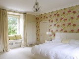 a chic bedroom with a floral wallpaper wall and matching textiles to make it chic and stylish