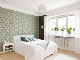 a white bedroom with a bright printed accent wall that takes over the whole space and gives tone to it