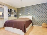 a neutral bedroom with a retro wallpaper accent wall that adds catchiness and brings style to the space