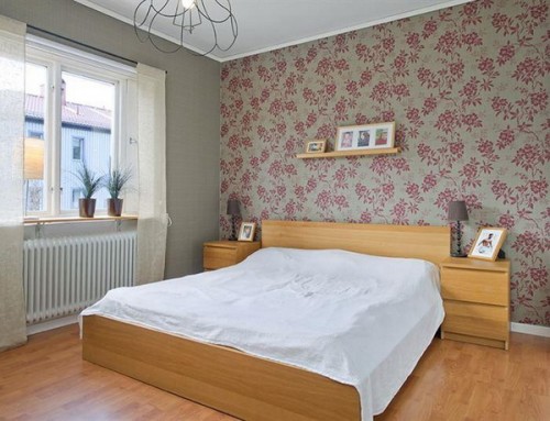 a grey bedroom with a grey and pink floral accent wall that gives a soft feel to the space