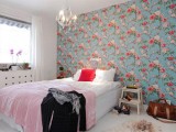 a colorful bedroom with a bright floral accent wall in blue and reds spruces up the whole room and makes it outstanding