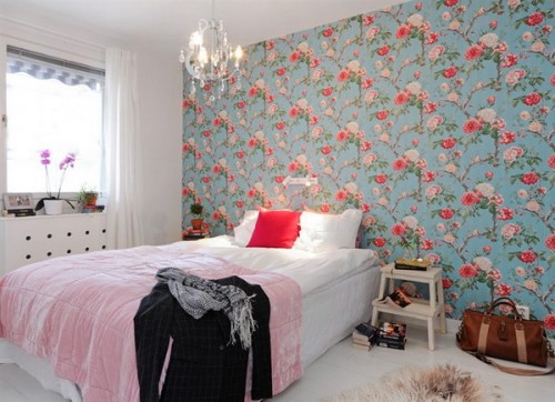 a colorful bedroom with a bright floral accent wall in blue and reds spruces up the whole room and makes it outstanding