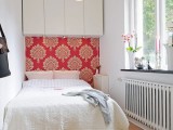 a small white bedroom refreshed with a single bright spot – a coral patterned accent wall behind the bed