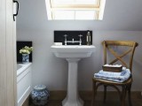 a small and cozy attic bathroom with a skylight, a bathtub, a chair and a free-standing sink is a functional space
