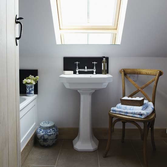 a small and cozy attic bathroom with a skylight, a bathtub, a chair and a free standing sink is a functional space
