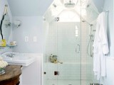 a tiny white attic bathroom with a skylight, a small shower space, a sink and vintage decor here and there