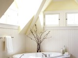 a neutral rustic attic bathroom with skylights and windows, with paneling, tiles and a built-in bathtub