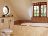 a warm attic bathroom clad with tiles in tan and brown, with several windows looks very inviting and cool