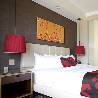 bright red pendant lamps and a bold artwork bring color and a whimsy touch to the bedroom