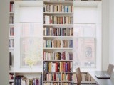 a bookshelf placed between the windows and under the windowsills that also forms natural seats for reading here