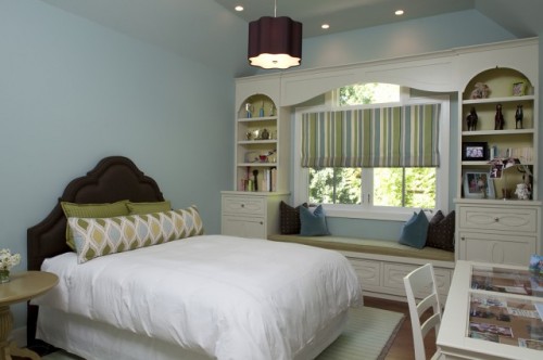 a cozy window seat with bright pillows and shelves on each side looks bright, fun and cool