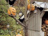 a tree with blackbirds, pumpkin lanterns and candel lanterns hanging on the tree is a chic Halloween decoration