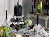 a silver vintage stand with black and grey pumpkins, black candles, spiderweb and spiders for creating an elegant Halloween tablescape
