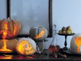 a scary Halloween console table with pretty carved pumpkin lanterns, poison in a bottle and some fruit is elegant