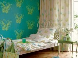 a turquoise wall with butterfly printing, printed bedding and curtains make the space look very quirky