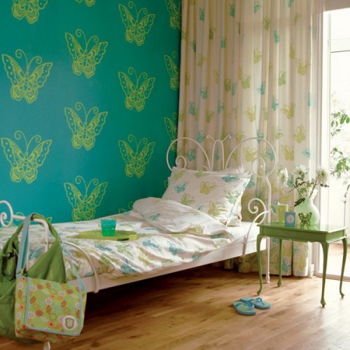 a turquoise wall with butterfly printing, printed bedding and curtains make the space look very quirky