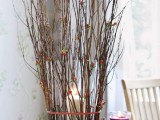 a glass candleholder wrapped with branches with berries is a cool natural idea and an easy DIY