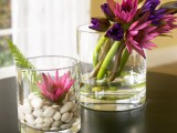 large glasses with pebbles, greenery and bright blooms can become chic decorations or centerpieces for the fall