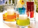 glasses with colorful water and pillar candles placed into them in other glasses look fun and bold