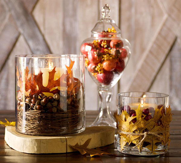 glasses with nuts, dried leaves, cranberries and candles and a jar with faux pomegranates is a cool fall centerpiece or decoration