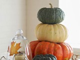 stacked pumpkins and fall leaves all around is a cool fall centerpiece with a strong natural feel