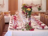 bright fall floral arrangements in vases and touches of burgundy accessorize wedding reception tables and make them feel like fall