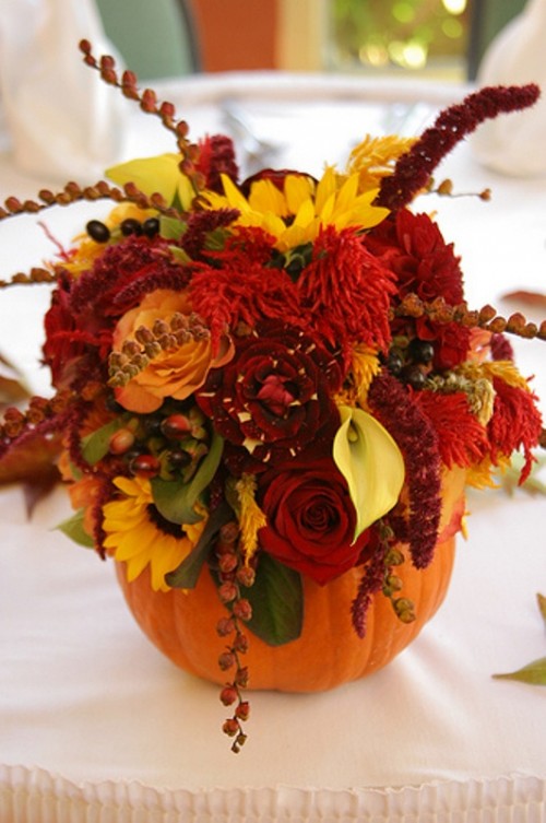 a pumpkin with bright and colorful fall blooms and leaves is a bold fall decoration or centerpiece