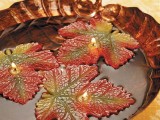 a leaf shaped bowl with bright leaf candles floating is a lovely fall decoration not only for a wedding
