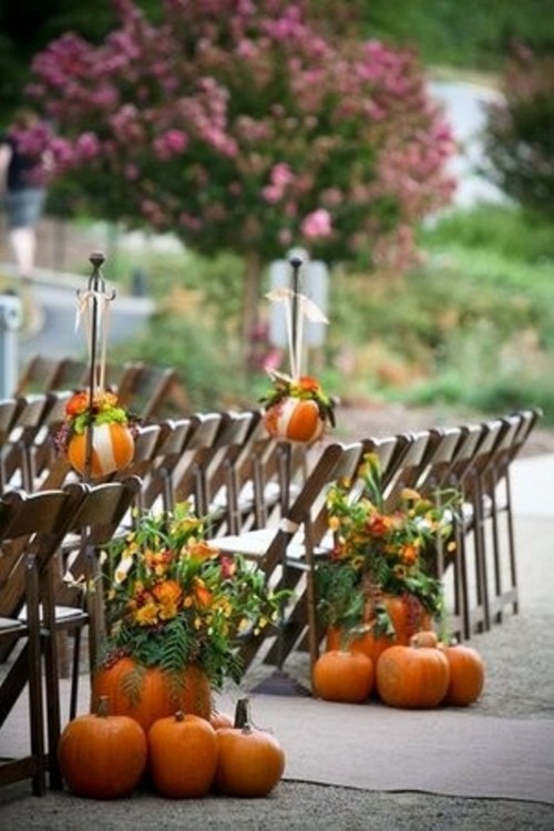 pumpkins and bright blooms and greenery in pumpkins decorate the wedding aisle in a cool rustic way