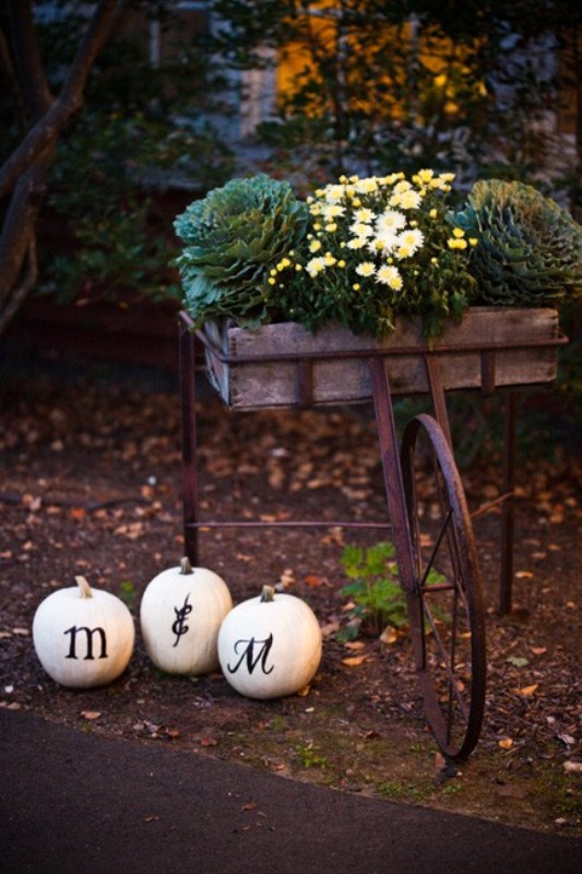 A cart with cabbages and white blooms and white pumpkins for decorating a wedding reception or ceremony space