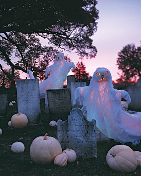 a graveyard with cheesecloth ghosts and gravestones is a nice front or backyard idea for Halloween