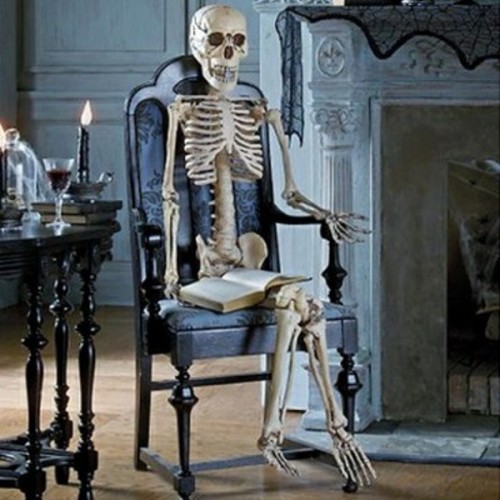 a skeleton in a vintage black chair is a stylish and refined idea of Halloween decor that is easy to make