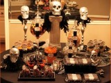 a Halloween decoration of skulls and feathers doubles as a stand for sweets for a Halloween party