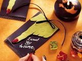 a black Halloween invitation with a monster hand and a bow is a cool bold idea