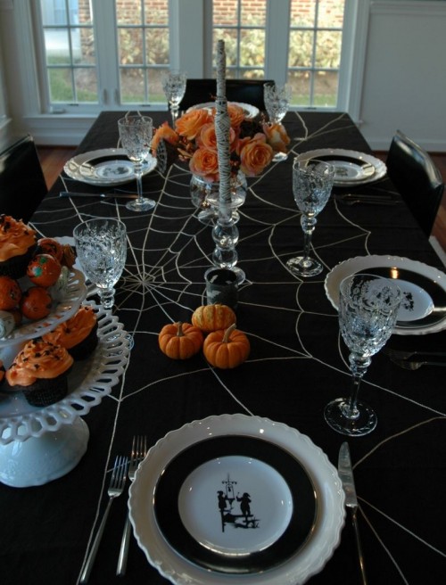 orange roses in a vase, a mummy candle and orange mini pumpkins for Halloween table decor