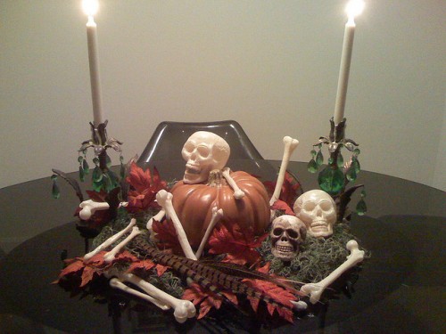 a Halloween centerpiece of a tray with moss, bones, skulls, feathers, leaves and a large pumpkin in the center