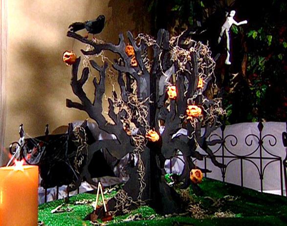 a black cardboard tree with pumpkins, blackbirds, skeletons and hay is a creative Halloween decoration or centerpiece