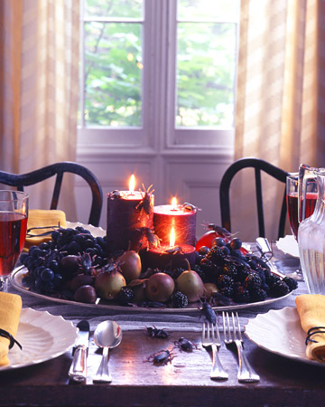 a decadent Halloween centerpiece of a bowl with grapes, blackberries, pears, apples and dark candles is very refined