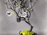 a quirky Halloween tree in black, in a black urn covered with moss and decorated with embroidery hoops with dark silhouettes and yellow apples