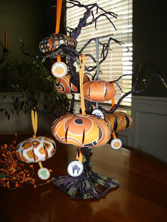 A black Halloween tree decorated with orange paper pumpkins on a stand is a bold and dramatic decoration