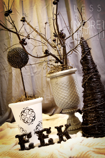 grey and black branches in a neutral vase, with black ornaments and beads glued to the branches
