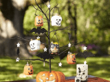 a black Halloween tree inserted into a pumpkin, with orange and white pumpkins and stars and owls for decor
